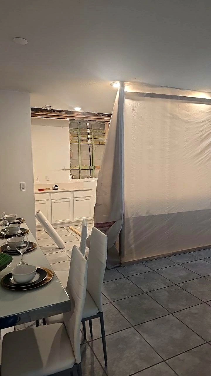 Plastic sheeting separates a work area beside the kitchen and dining space.