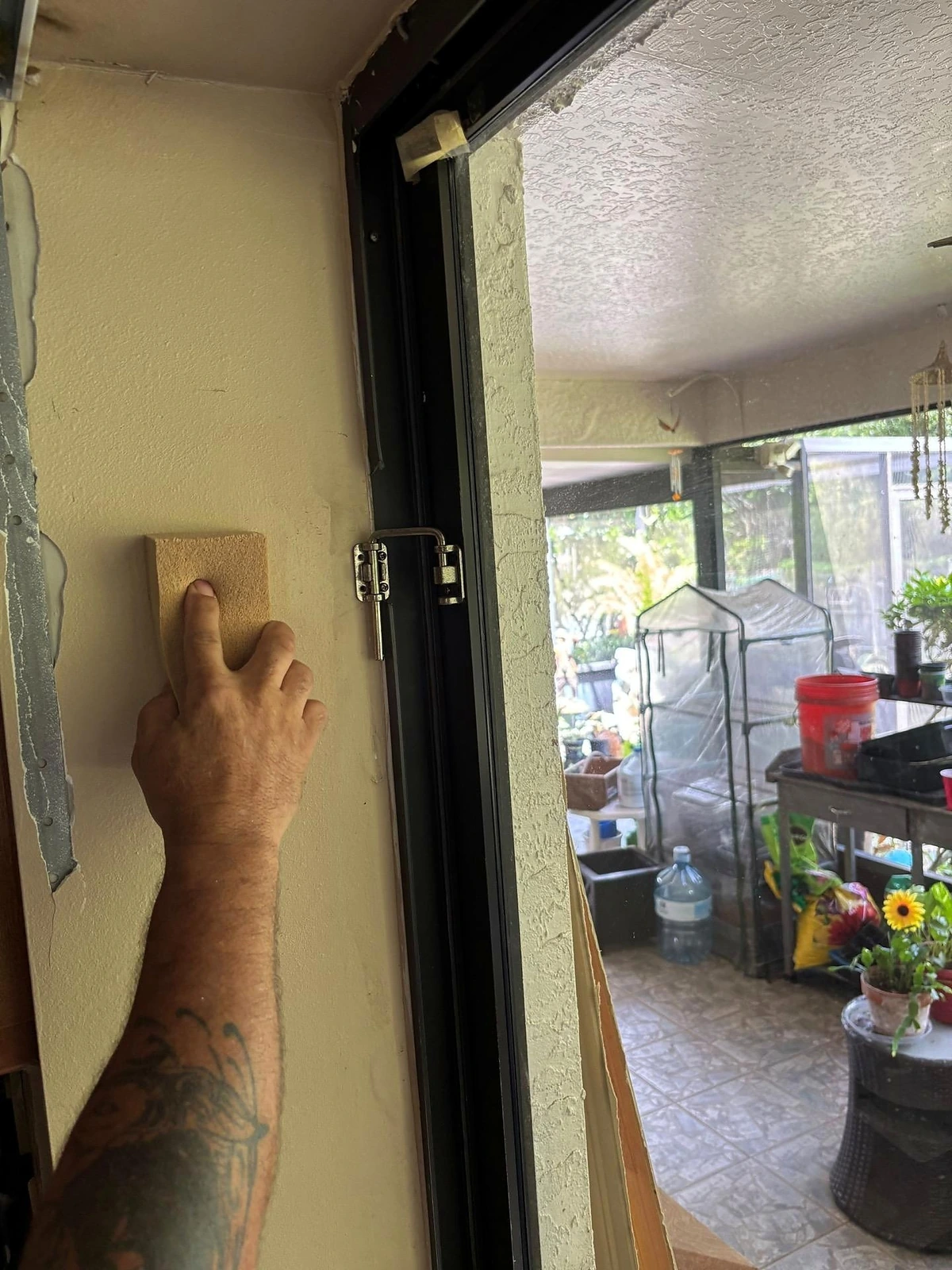 Se utiliza una esponja para hollín para limpiar la pared junto a una puerta corrediza de vidrio.
