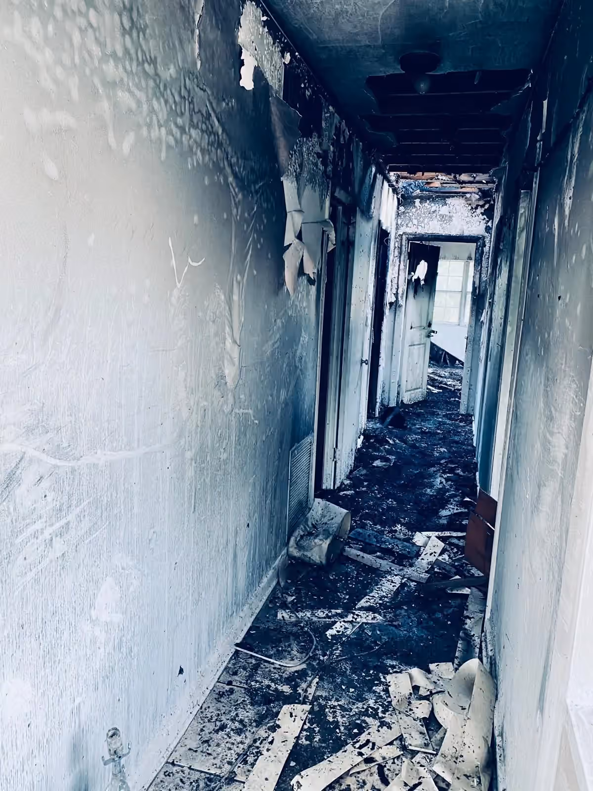 Corredor danificado pelo fogo com detritos no chão