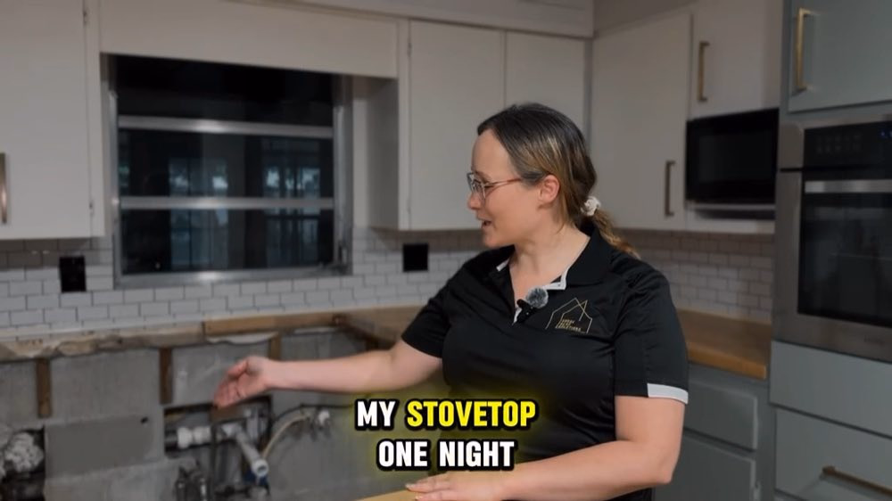 Mulher de mão estendida junto à parede aberta da cozinha