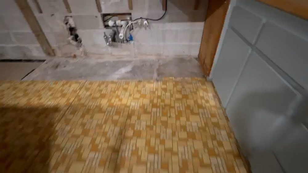 Carrelage jaune sous la plomberie exposée et la charpente murale