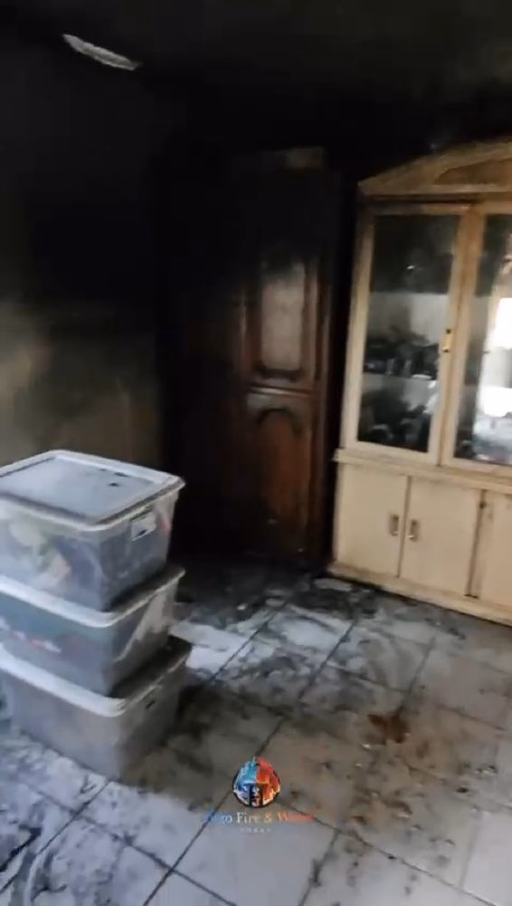 Fire-damaged room with stacked containers and a cabinet