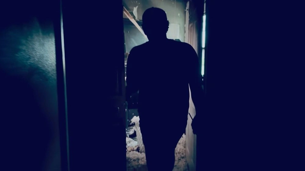 Pessoa andando por um corredor escuro e danificado