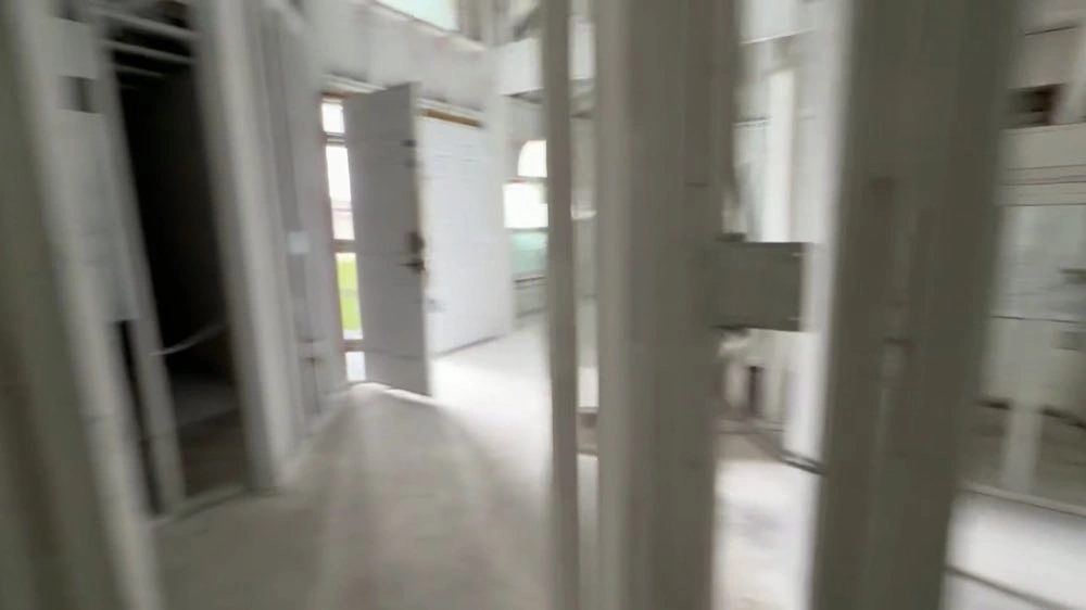 Exposed studs frame a view into the adjoining interior space