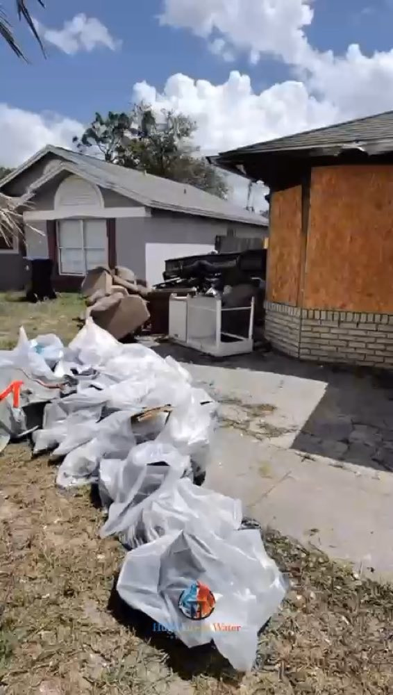 Escombros en bolsas afuera de una casa con una abertura tapiada