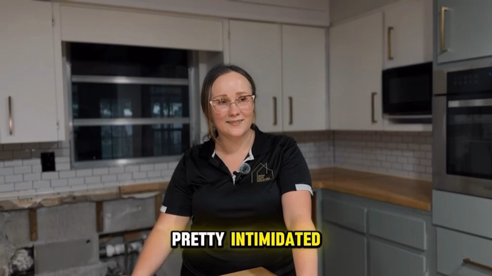 Woman wearing a lapel microphone beside opened lower kitchen walls