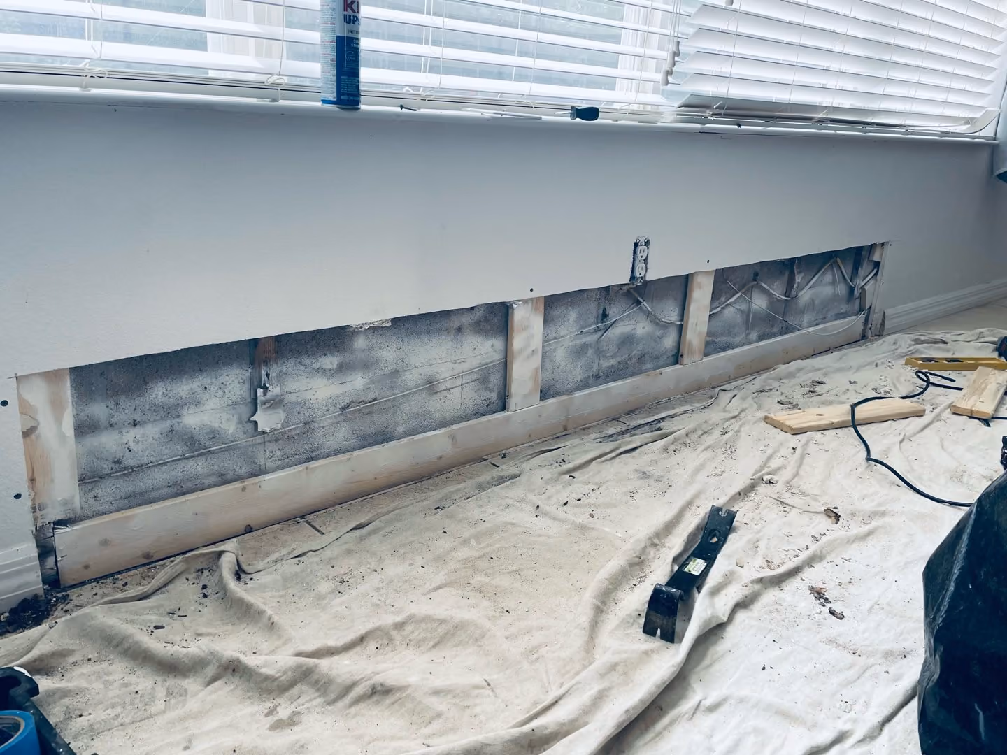 Pared abierta bajo una ventana, con estructura y manchas oscuras